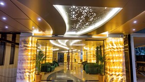 Eine moderne Hotellobby mit gewölbter Decke, spiegelndem Boden und grünen Sitzbereichen.