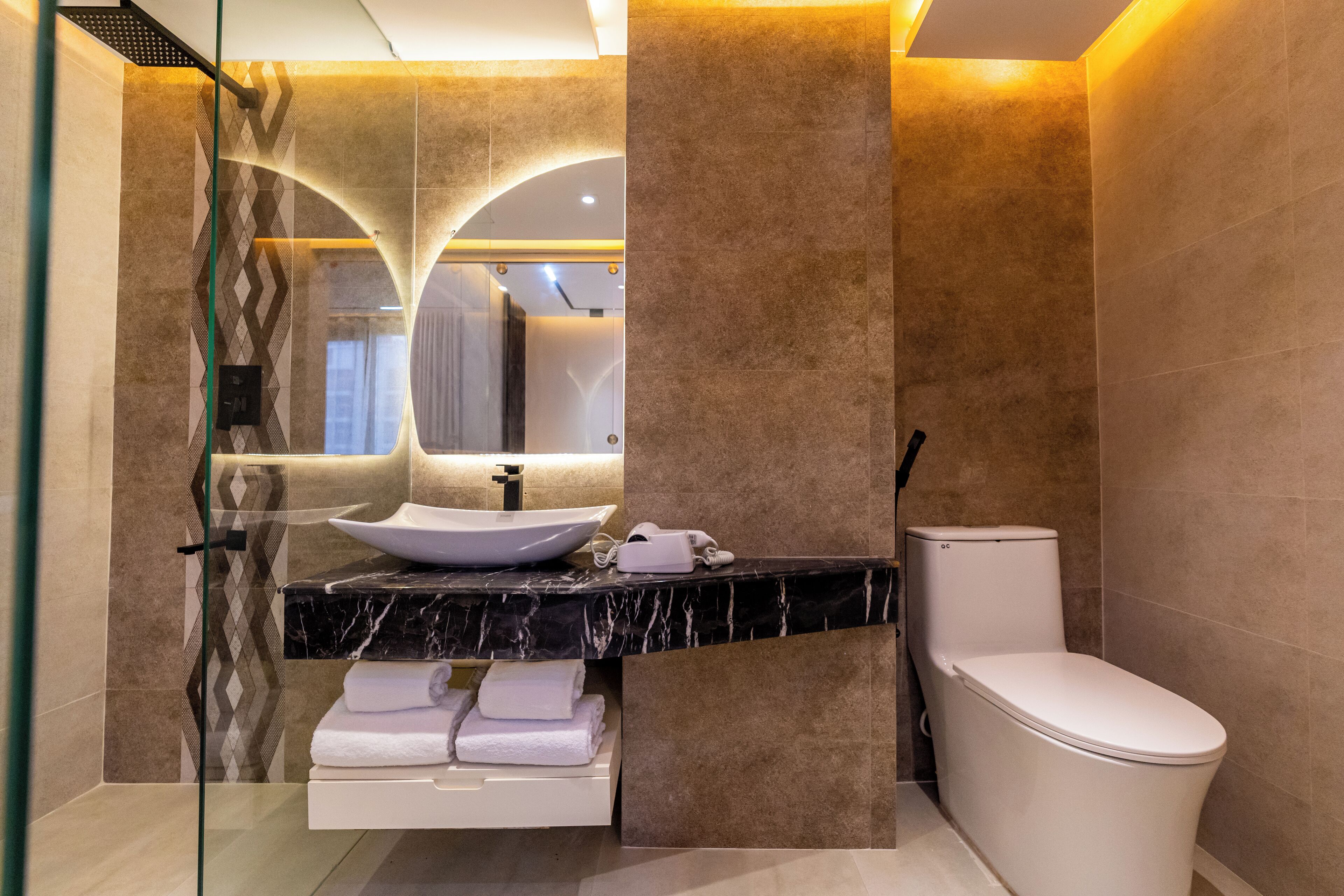 A modern bathroom with a marble countertop, a white sink, and a toilet.