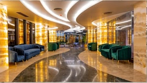 Eine moderne Lobby mit gewölbten Deckenleuchten, Marmorsäulen und komfortablen Sitzbereichen.