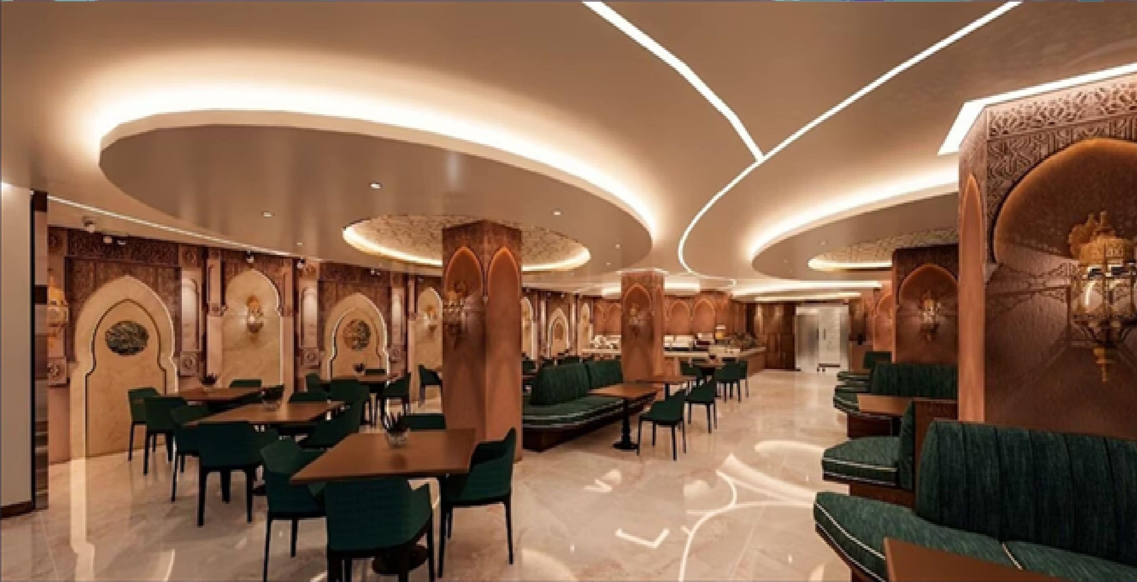 A spacious hotel lobby with a modern design, featuring a central seating area with tables and chairs, and a decorative wall with arches.