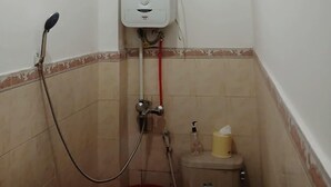 Ein kleines Badezimmer mit Dusche, Fenster und Toilette.