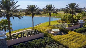 Ein Resort namens 'SOLARA' mit einem Schild, Palmen, einem See und einem Golfplatz im Hintergrund.
