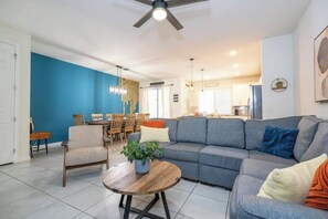 Una sala de estar con sofá, sillones, una mesa de centro y un comedor con sillas y una mesa.