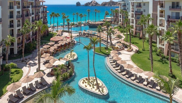 Un resort con múltiples piscinas, palmeras y vistas a la playa.