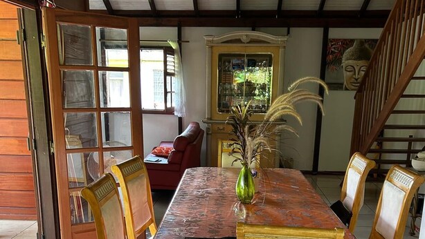 Un comedor con una mesa y sillas de madera, un florero con plantas secas y una estatua de Buda en la pared.