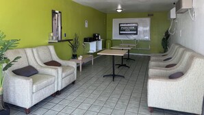 A hotel lobby with green walls, two sofas, a coffee station, a whiteboard with 'PARKSIDE INN' signage, and tiled flooring. - Parkside Inn by PHG - Sweetwater (Sweetwater)