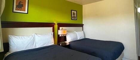 A hotel room with two beds, a green wall, and a ceiling light.