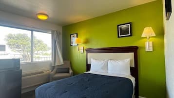 A hotel room with a large bed, a desk, and a window.