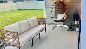 A covered patio with a wicker sofa, a hanging chair, string lights, and potted plants. - SPRING HAVEN RETREAT! A BEUTIFULL ANDSPOTLESS!! (Newberry)