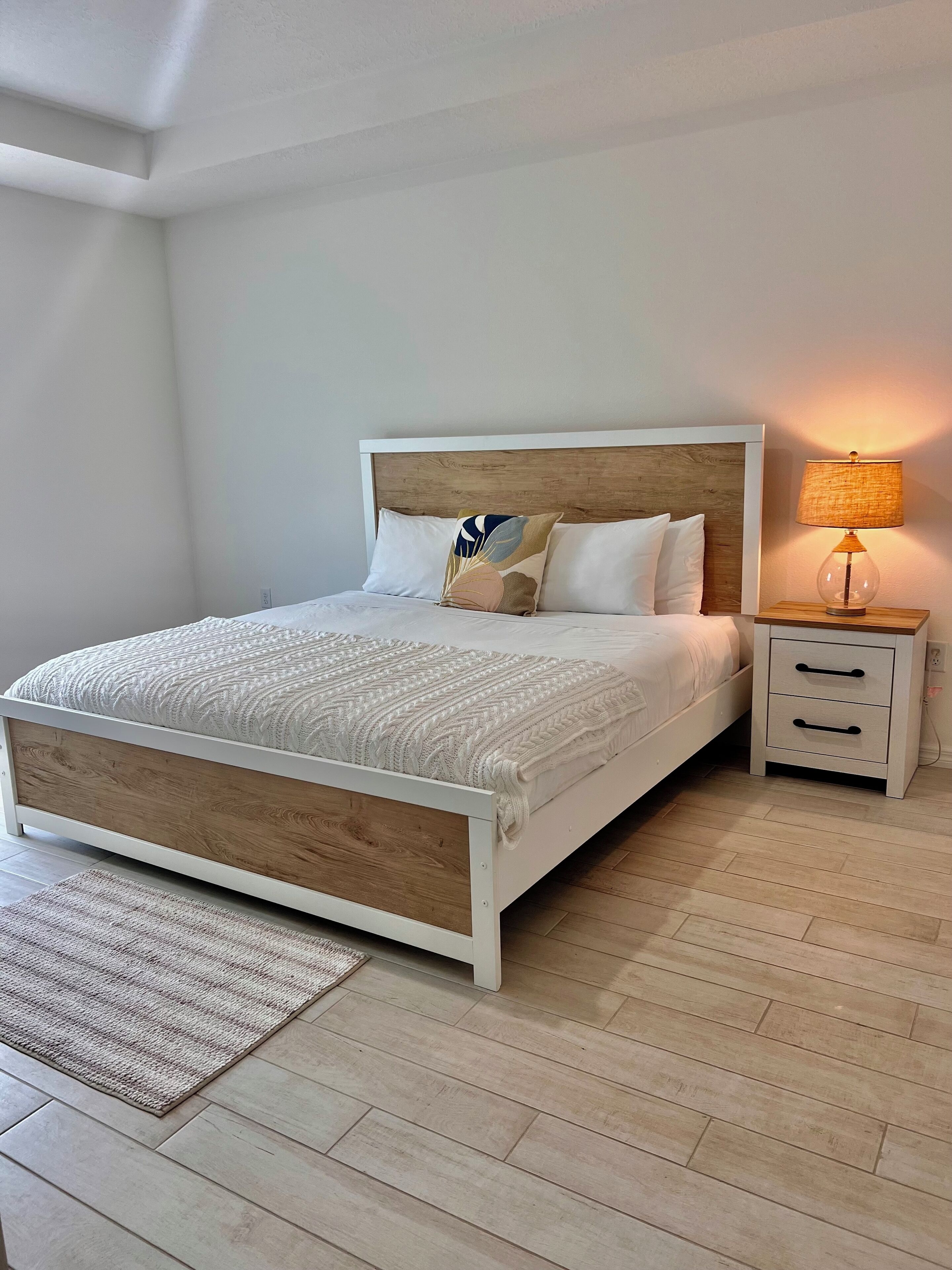 A bedroom with a bed, nightstand, and lamp.