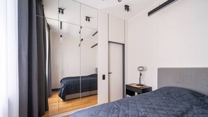 A modern bedroom with a bed, a bedside table with a lamp, and a large mirror.