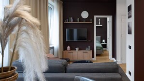 Un salon moderne avec un canapé gris, un téléviseur fixé au mur et un meuble en bois.