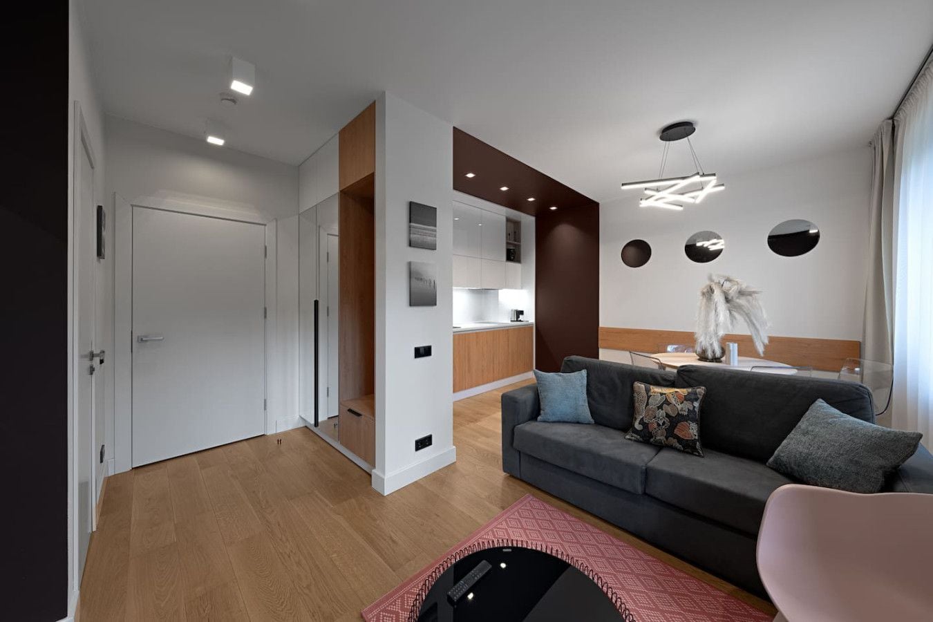 Una sala de estar moderna con un sofá gris, una mesa de centro y un comedor con una mesa y sillas de madera.