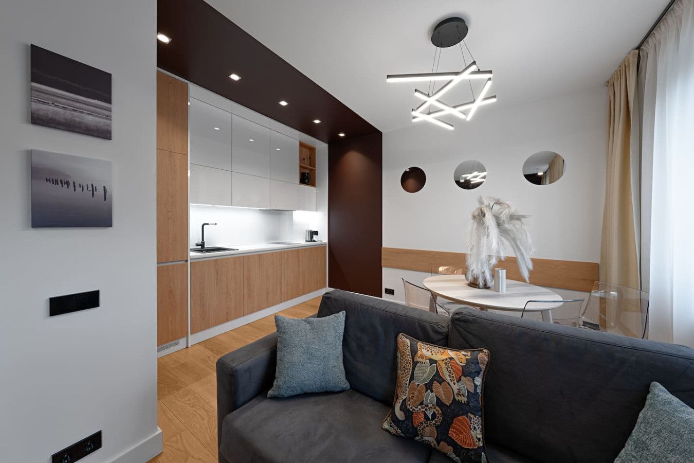 Una cocina moderna con armarios blancos, encimera de madera y zona de comedor con mesa y sillas blancas.