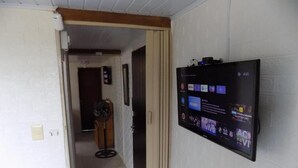 Un pasillo con un televisor de pared que muestra varias aplicaciones y un reloj marcando las 4:41.