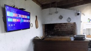 Una cocina con horno de ladrillo, taburetes de madera y un televisor de pantalla plana montado en la pared.