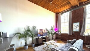 Una sala de estar moderna con techo de madera, un sofá, una mesa de centro y plantas en macetas.
