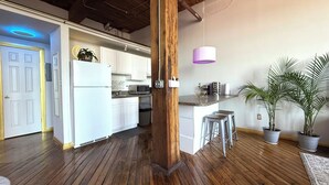 Una cocina moderna con armarios blancos, suelo de madera y una lámpara colgante.