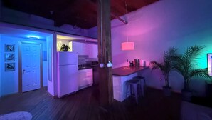 Una cocina moderna con una isla central, taburetes de bar y una lámpara colgante iluminada con neón.