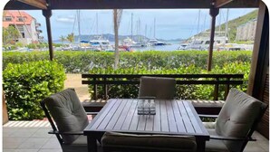 An outdoor patio with a table and chairs, overlooking a marina with boats. - Charming condo walking distance to Sapphire Beach, St Thomas (St Thomas)