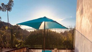 A wooden deck with a table and chairs under a blue umbrella.