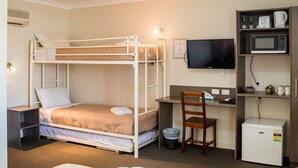 Ein Hotelzimmer mit Etagenbett, Schreibtisch, Fernseher, Mikrowelle und kleinem Kühlschrank.