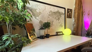A desk with a world map, a potted plant, a lantern, and a neon light. - Downtown: River’s Edge Industrial Loft (Detroit)