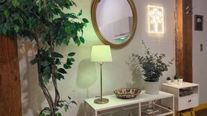 A room with a wooden door, a mirror, a lamp, a shelf with decorative items, and a potted plant. - Downtown: River’s Edge Industrial Loft (Detroit)