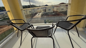 A balcony with two chairs and a small table, overlooking a residential area with houses and a road. - Charming 3-bedroom villa in Ocho Rios with a view of the Caribbean Sea (Ocho Rios)