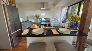 A modern kitchen with a central island, stainless steel appliances, and a view of the outdoors.