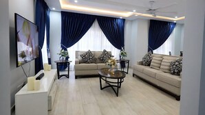 A modern living room with a sofa set, a coffee table, and a TV. - Spacious 2BR private apartment setting for families near Accra. (Oyibi)
