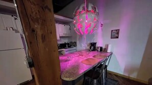 A kitchen with a pink-lit pendant light, a wooden beam, and a refrigerator. - Downtown: Cinema Loft w/ Projector (Detroit)
