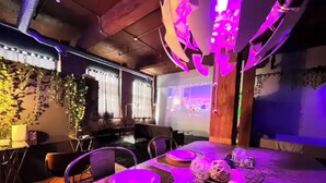 A modern dining area with a table set for four, a projector screen, and ambient lighting. - Downtown: Cinema Loft w/ Projector (Detroit)