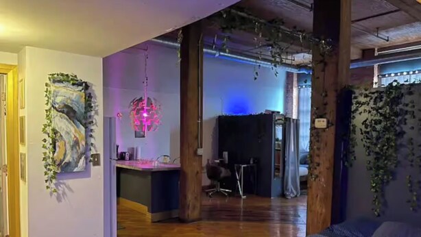 A modern room with a wooden floor, a desk with a computer, a chair, and a bed with a gray blanket. - Downtown: Cinema Loft w/ Projector (Detroit)