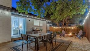 En baghavepatio med spisebord, stole og bålsted.