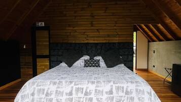 Ein Schlafzimmer mit einem großen Bett, Holzbalken, einer Steinwand und einem kleinen Fenster.