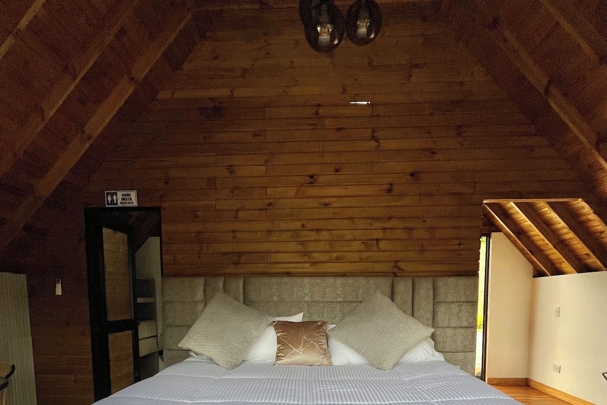 A room with a bed, wooden beams, and a ceiling light fixture.