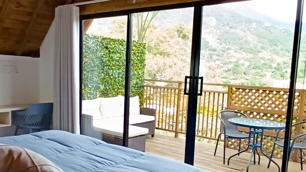 A bedroom with a large bed, a desk, and a view of a balcony with outdoor furniture. - Hotel Noral Lemont (Copacabana)