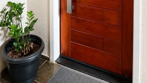 A wooden door with a keypad lock, a potted plant, and a number sign above it. - Entire Apartment (Paulo VI Belo Horizonte)
