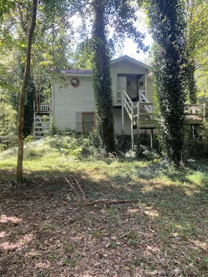 Een houten chalet met een klein terras en een trap naar een dek.