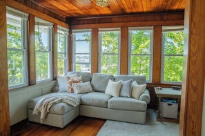 Una habitación acogedora con un sofá modular, una mesita y un ventanal con vistas a los árboles.