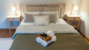 Una cama bien hecha con un cabecero de madera, dos mesitas de noche con lámparas y una bandeja con artículos de tocador sobre la cama.