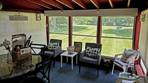 Una habitación acogedora con techo de madera, una mesa con sillas y ventanas amplias que dan a un césped verde.