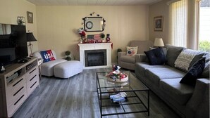 Una sala de estar con chimenea, un sofá, una mesa de centro y un televisor.