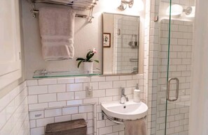 Une salle de bain avec une douche à parois de verre, un lavabo blanc et un porte-serviettes.