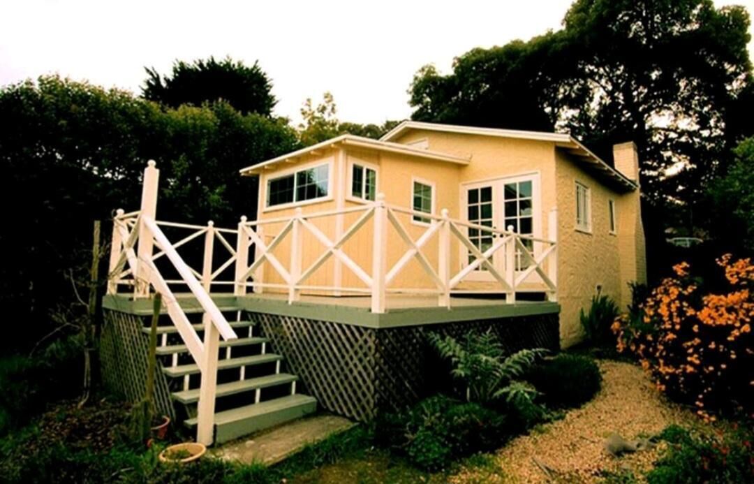 A two-story house with a wooden deck and stairs leading to a balcony.