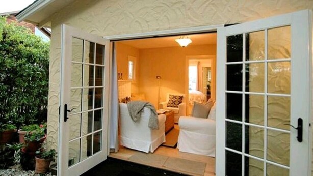 A cozy room with a bed, a chair, and a small table. There is a door leading outside. - Charming 1-bedroom cottage in gorgeous Monterey (Monterey)