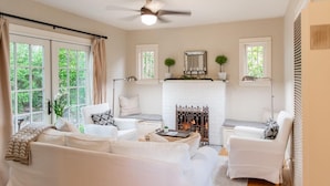 A living room with white furniture, a fireplace, and large windows. - Charming 1-bedroom cottage in gorgeous Monterey (Monterey)