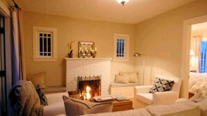 A cozy living room with a fireplace, a sofa, and a chair. - Charming 1-bedroom cottage in gorgeous Monterey (Monterey)