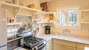 A kitchen with a stove, microwave, and various utensils on shelves. - Charming 1-bedroom cottage in gorgeous Monterey (Monterey)